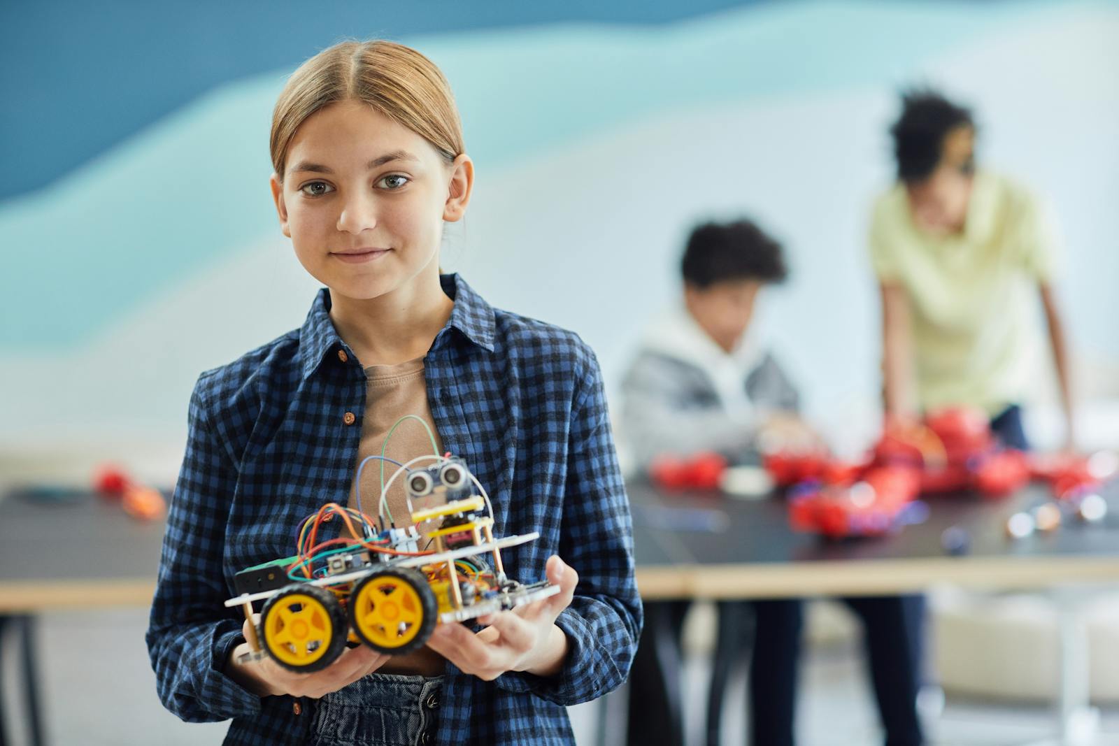 Girl proudly displays her robotics project in a classroom setting.